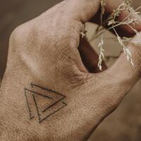 Tattoo depicting a valknut symbol in black ink